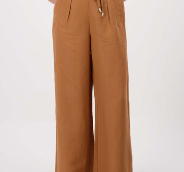 Linnen broek met riempje warm camel van Zusss; model draagt witte top en sandalen.