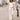 crincle broek | kit van Zusss, een vrouw wandelt rustig door een straat in neutrale tinten met een gebreide tas.