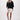 The model is wearing a black V-neck woven top with zigzag detailing by Zusss, a loose-fitting V-neck top.