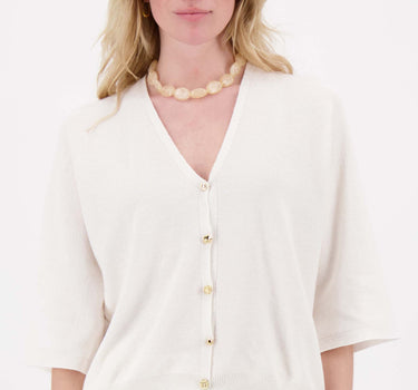 Model draagt off white vestje met leuke knopen van Zusss, zacht gebreid vest met goudkleurige knopen.