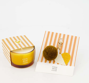 Set van een Ansichtkaart en geurkaars van Zusss, oranje gestreepte verpakking met amberkleurige kaars.