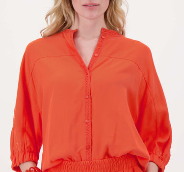 Coral-colored lyocell blouse with balloon sleeves by Zusss; the model is wearing a blouse with a lace trim along the button placket.