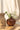 A small "Terra" terracotta heart-shaped vase by Zusss in a charming living room still life featuring a flower and a wooden candleholder.